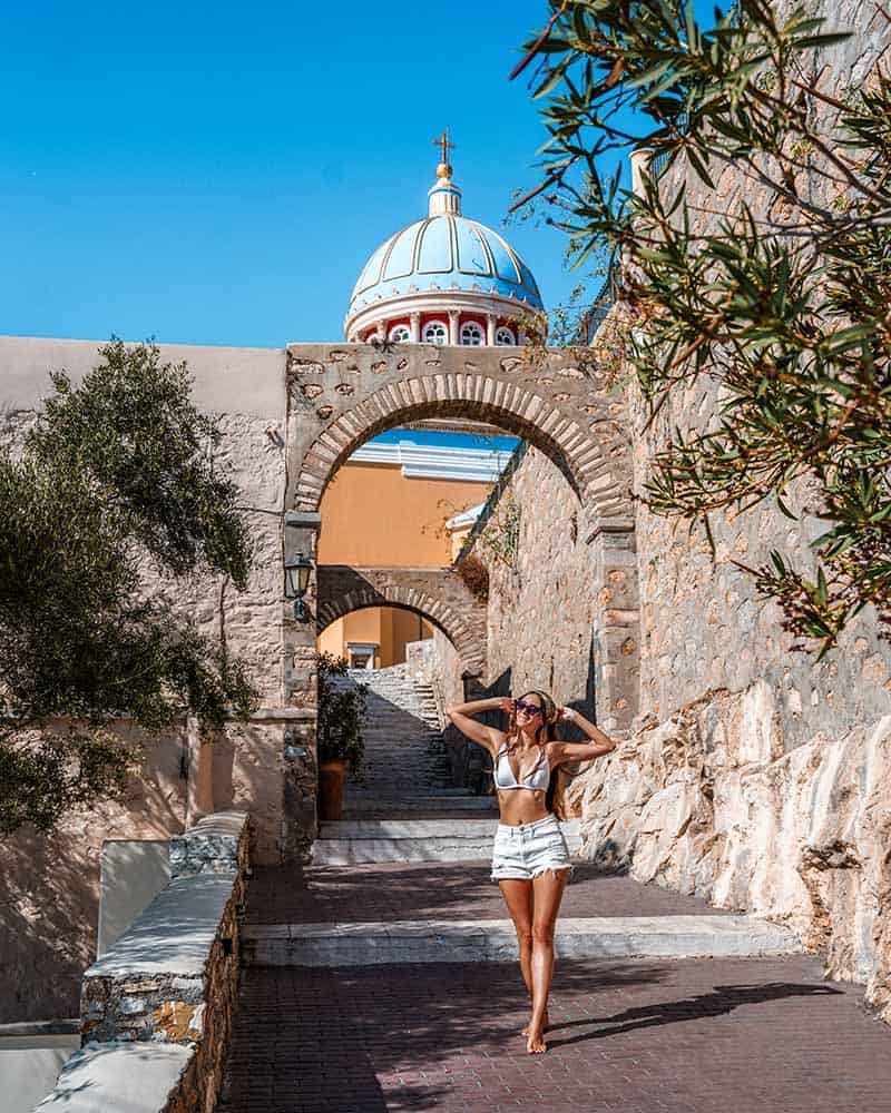 A photo of me enjoying the sun in Syros, with the iconic church of Ermoupoli in the background.