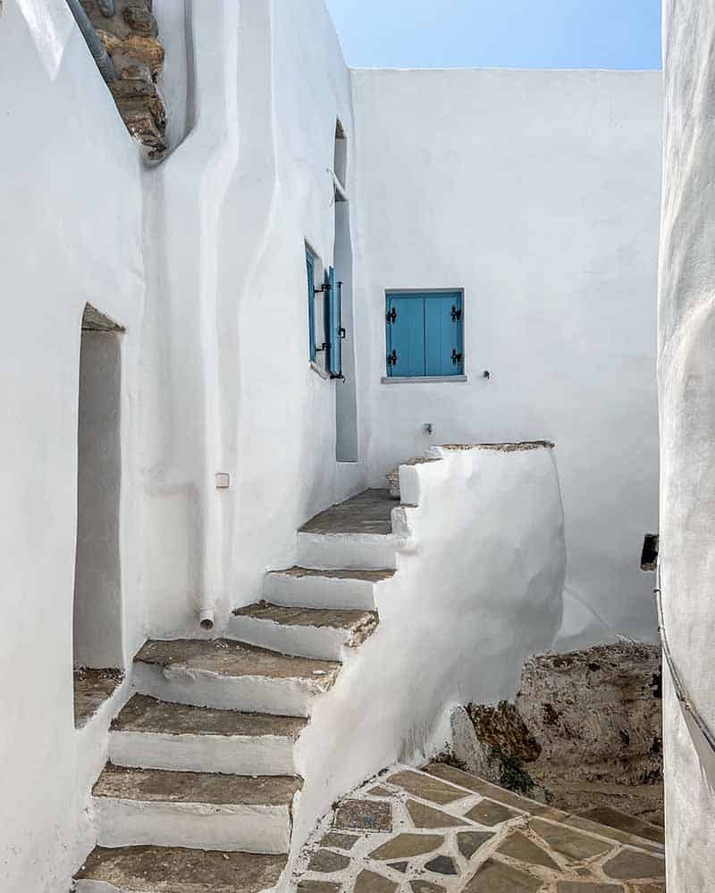 Traditional Cycladic architecture in Tinos: White building with blue windows and white stairs