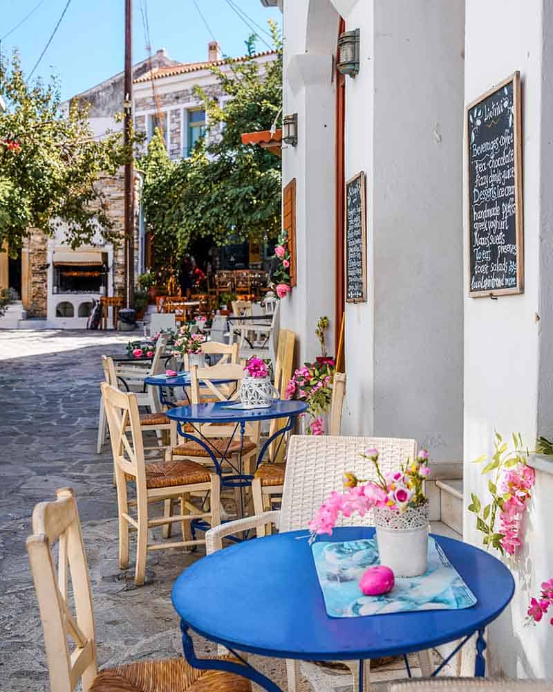 A cute open-air restaurant with blue tables, nestled in the heart of a quaint village in Naxos.
