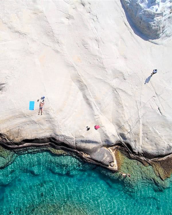 A breathtaking aerial view of Sarakiniko Beach reveals its stunning white cliffs contrasting against the crystal-clear turquoise waters.