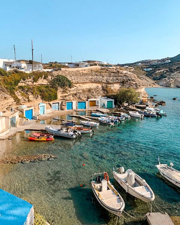 Small boats anchoring in the crystal-clear waters of a picturesque bay in Milos.