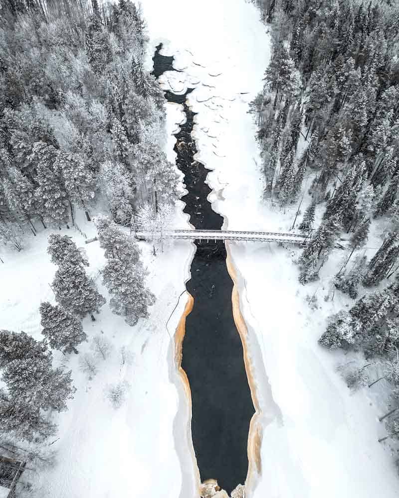 Aerial view of a frozen river surrounded by snow-covered trees