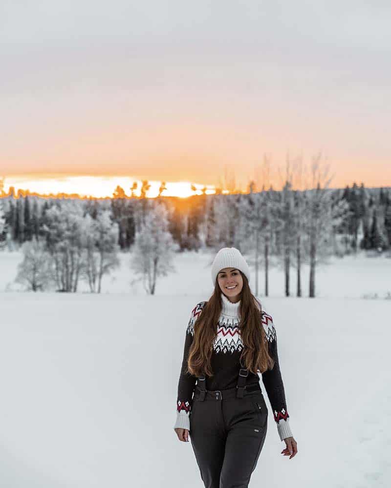 Me wearing a white hat, black ski pants and a woolen jumper with nordic motifs.