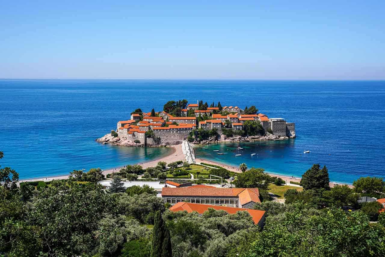 The small island of Sveti Stefan surrounded by deep blue water on a beautiful summer day
