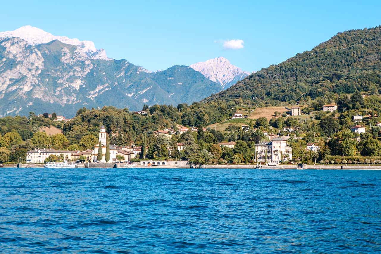 View of a small town in Lake Como from the water with mountains in the background